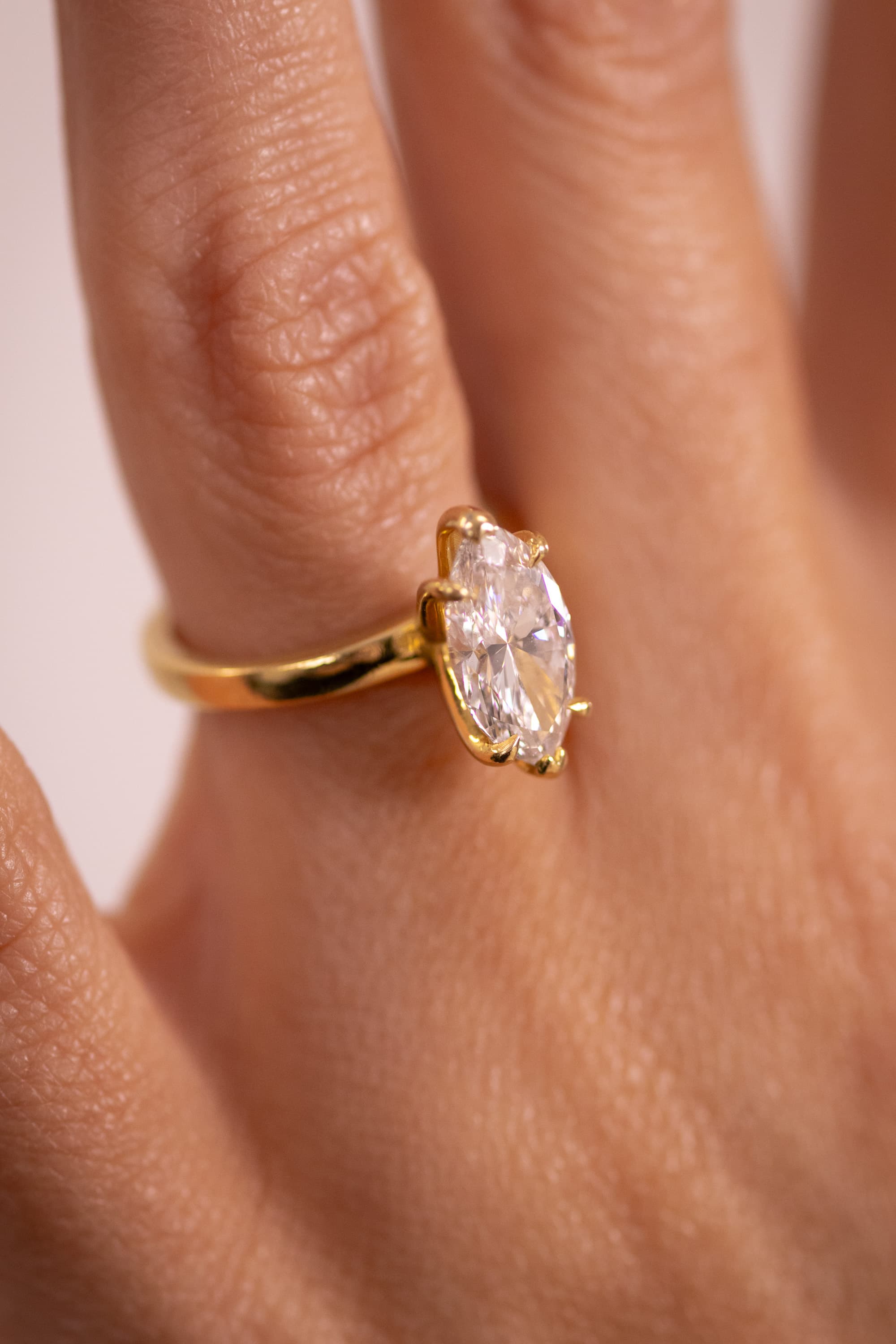 A finished yellow gold oval halo engagement ring in an open navy presentation box