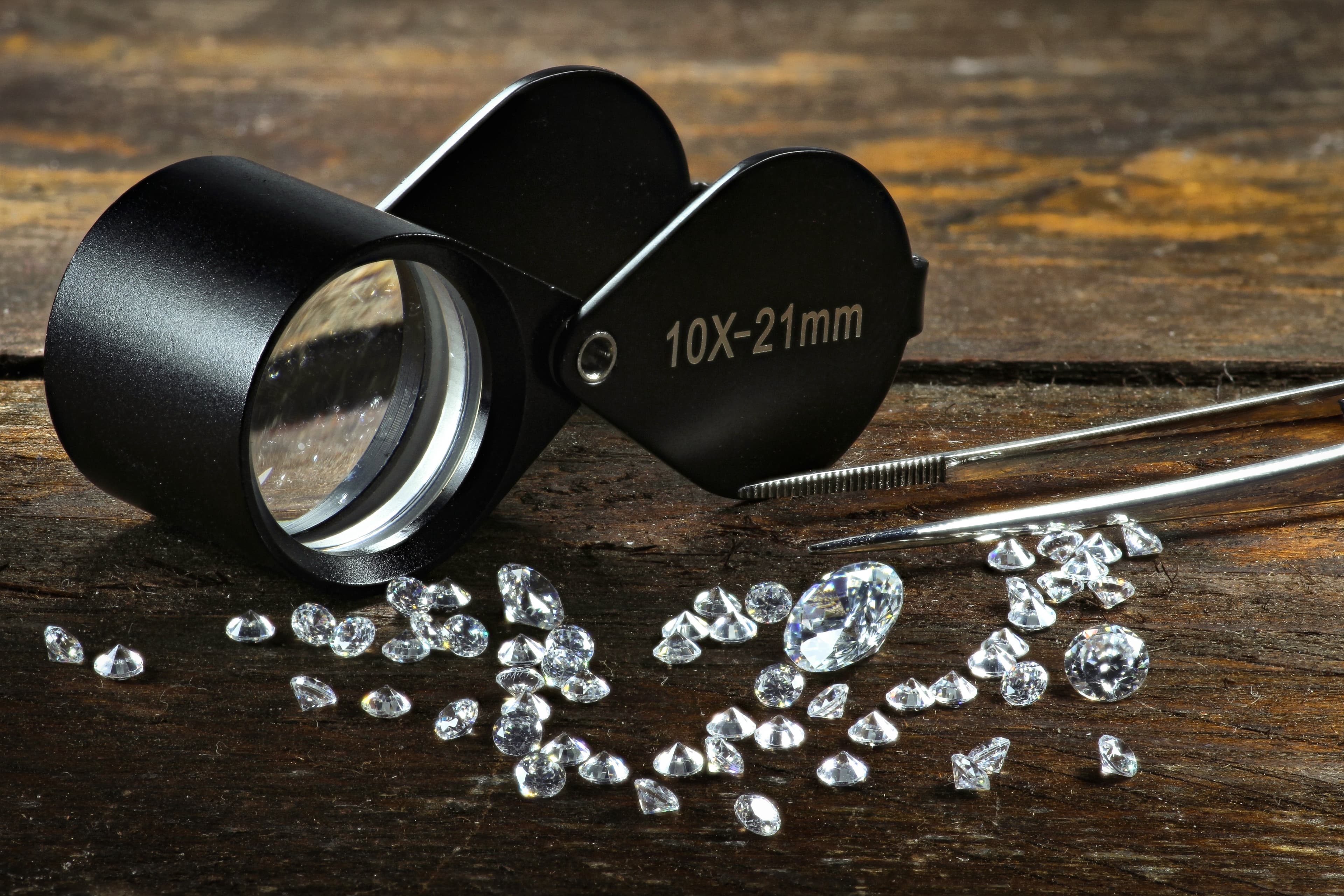 A brass folding loupe resting over a loose diamond