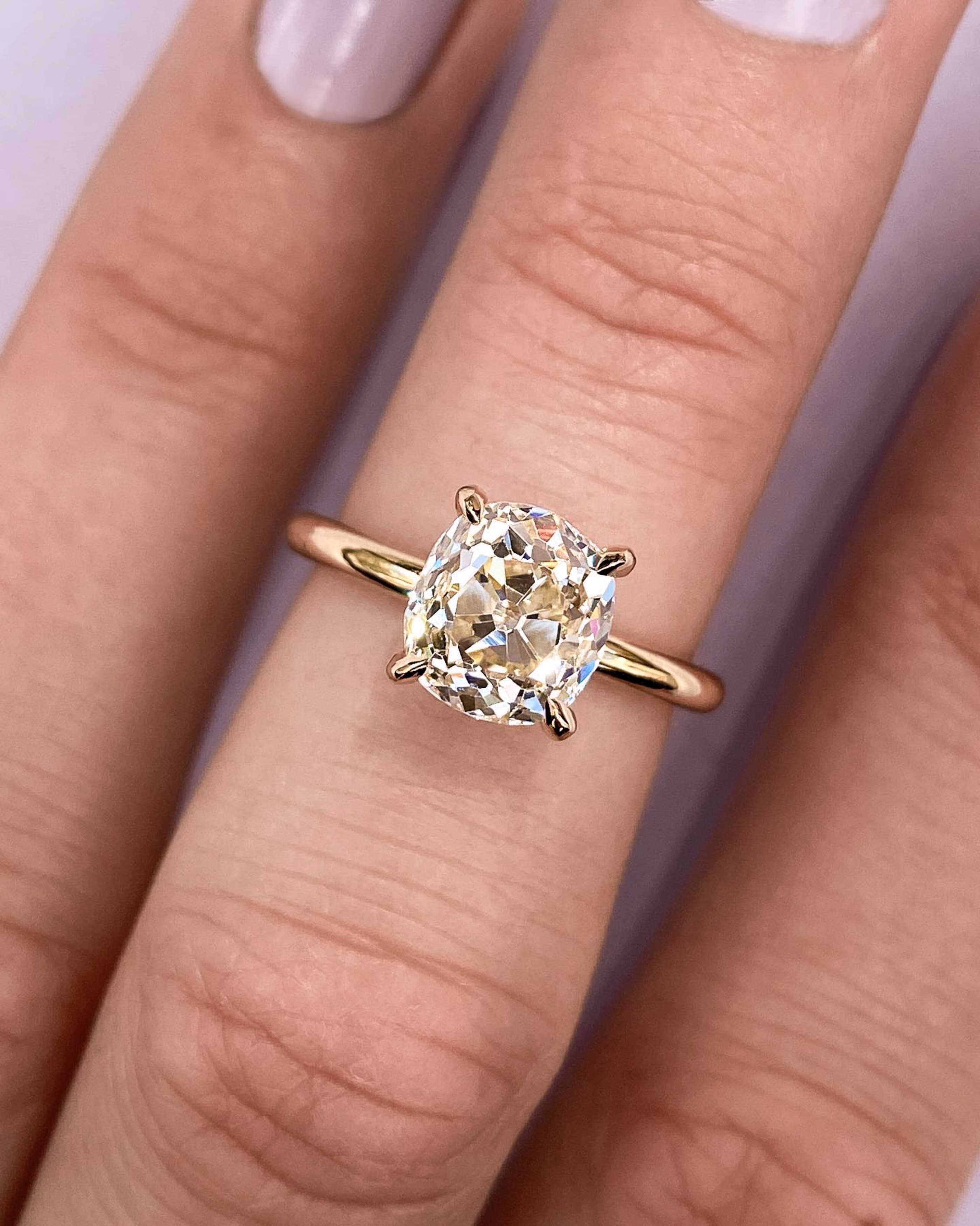 A vintage yellow gold ring with milgrain beading holding an old-cut cushion stone