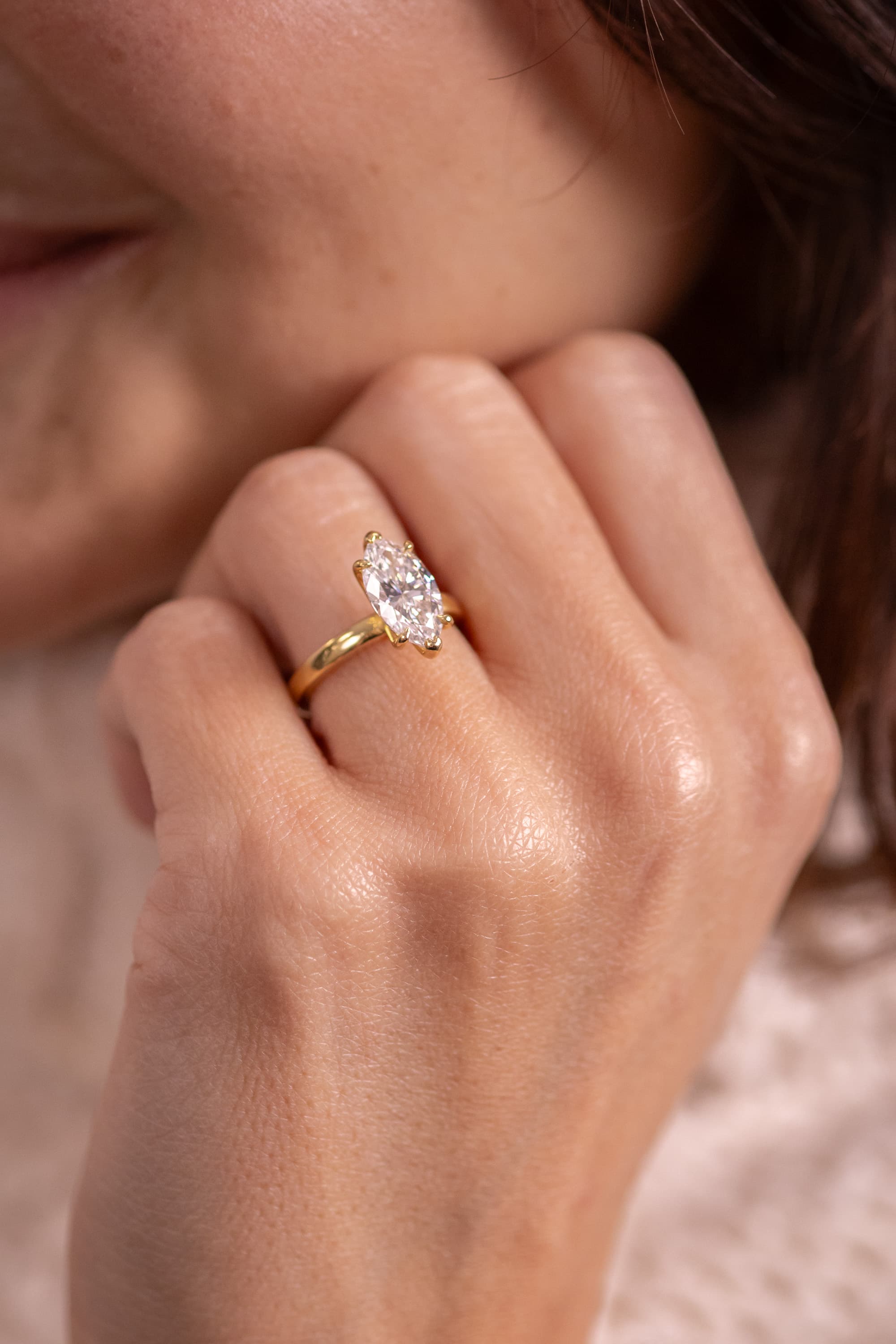 A large three-carat oval lab-grown diamond solitaire in yellow gold on a fine band