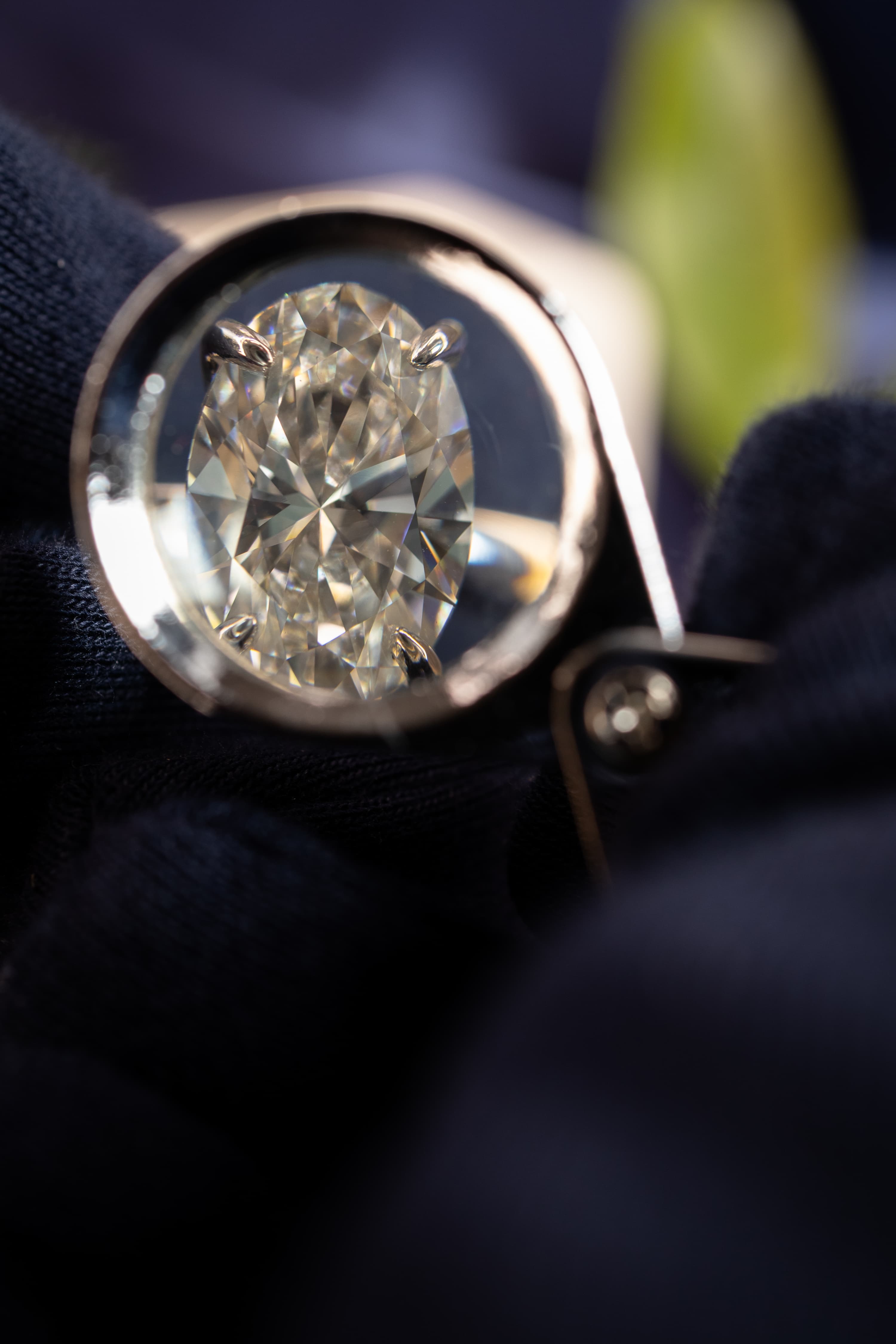 Five loose diamonds in different cuts — baguette, heart, round, oval and emerald — each held in jeweller's tweezers