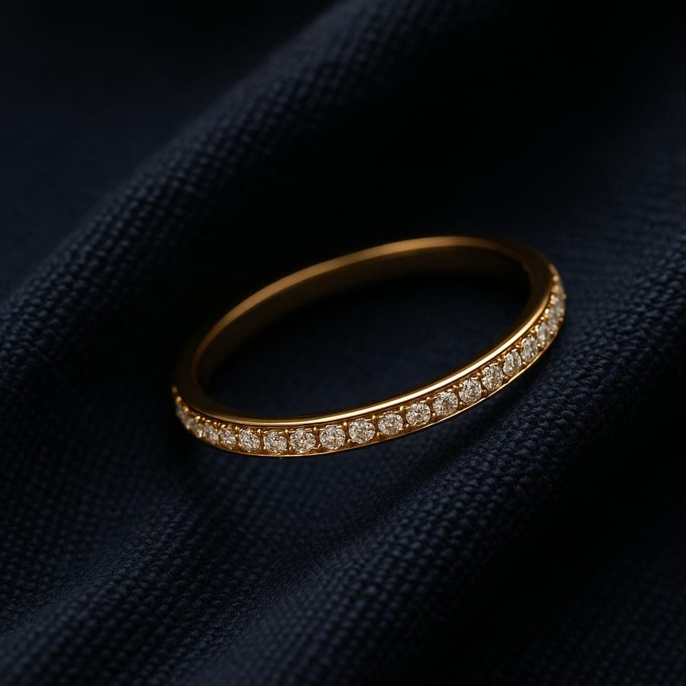 A slim yellow gold pavé-set wedding band with a line of tiny diamonds along the top