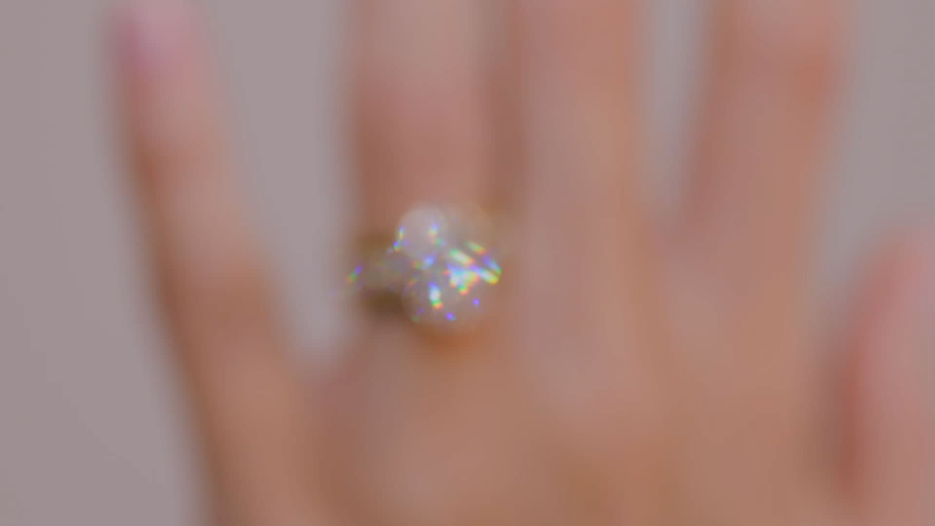 A softly blurred close-up of a diamond engagement ring on a hand, coming into focus