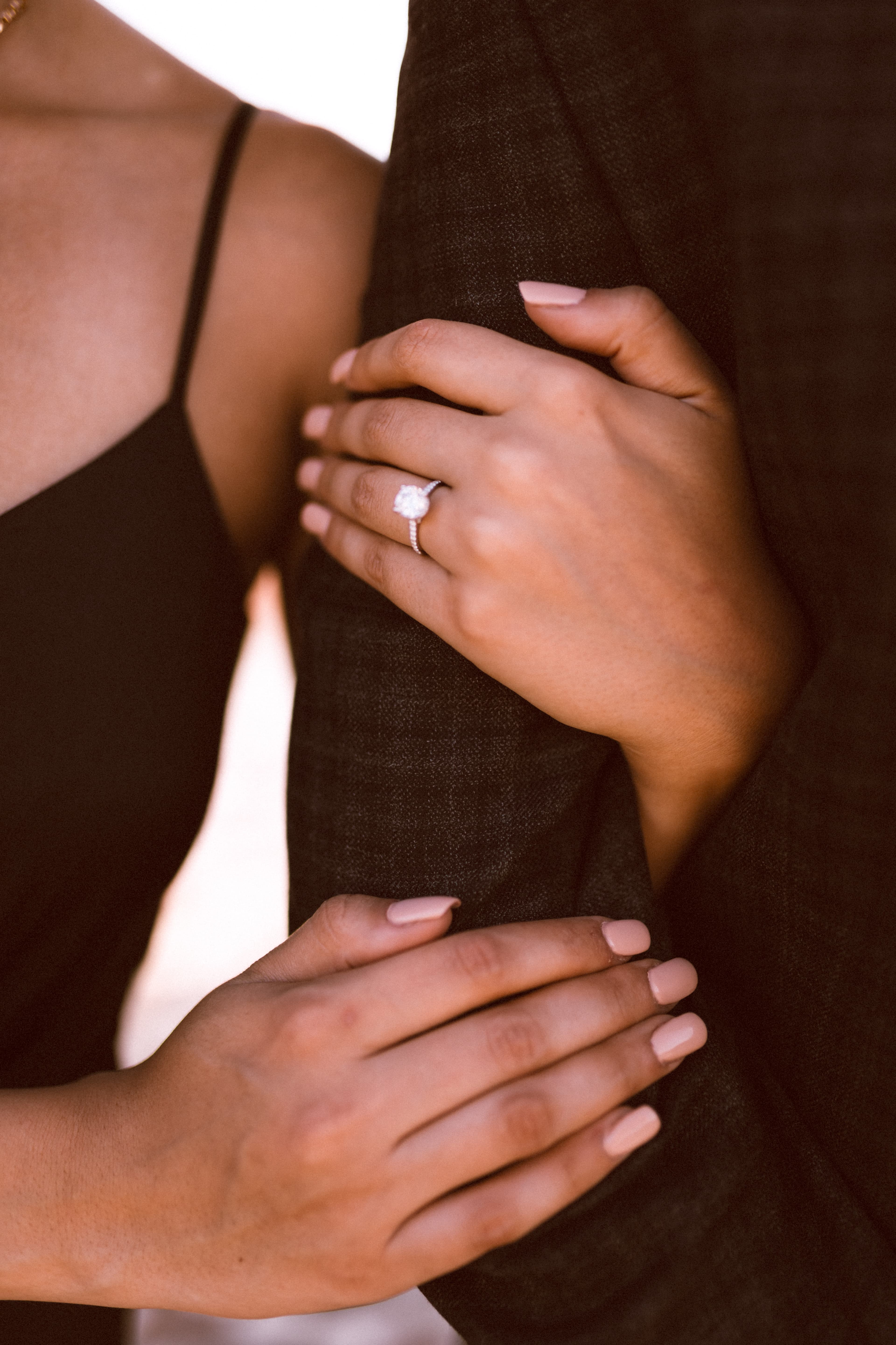 A couple on a coastal clifftop at sunset, one down on one knee proposing